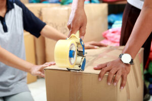 portrait of worker using duck tape for packing product into a box at textile factory